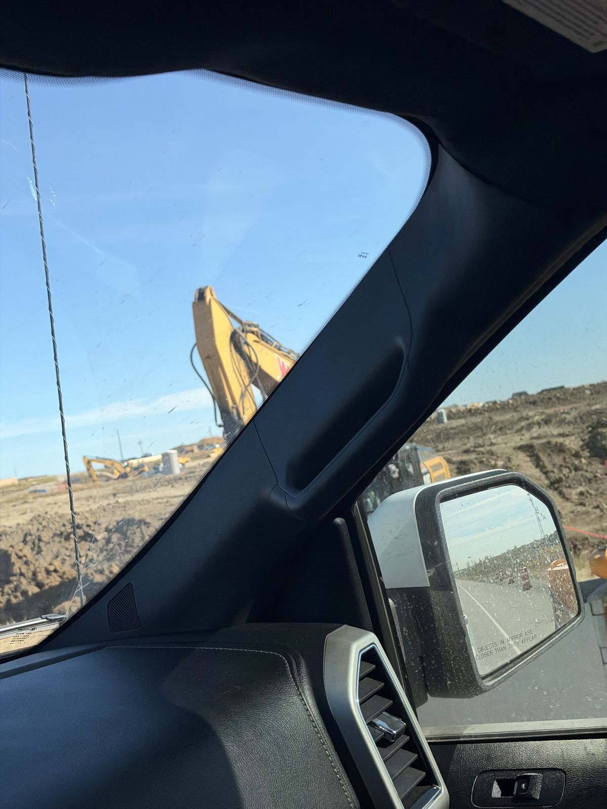 Excavator working on Memorial Drive extension seen from a vehicle window